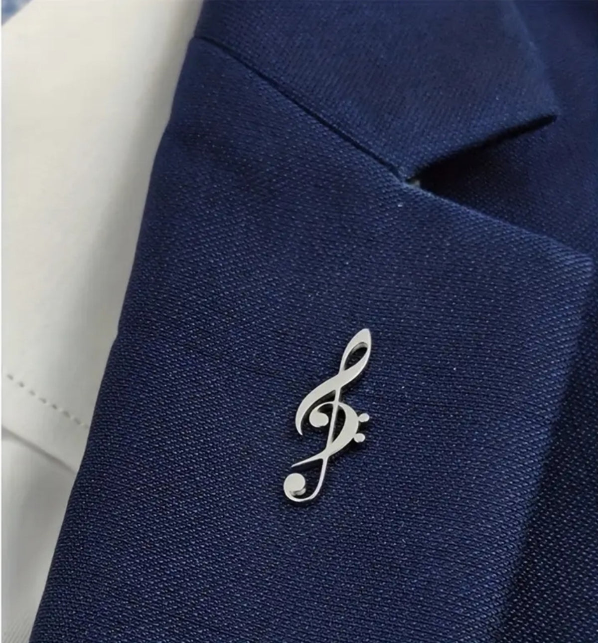 Pin clave de sol plateado colocado en chaqueta de vestir